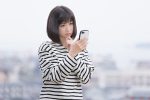 スマホを見て悩む女性